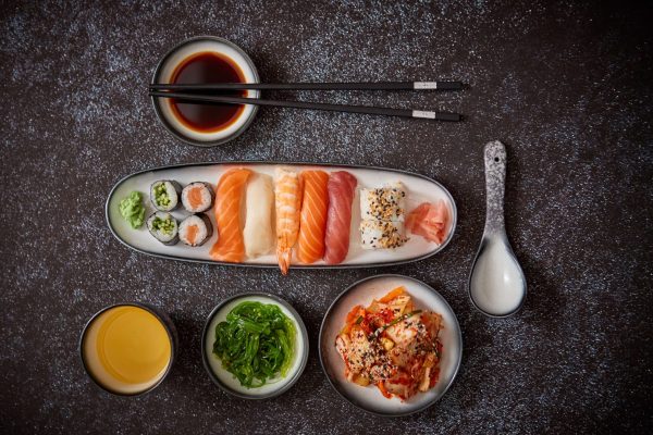 asian-food-assortment-various-sushi-rolls-placed-ceramic-plates-kimchi-goma-wakame-salads-soy-souce-chopsticks-sides-grungy-dark-background-with-copy-space (1)